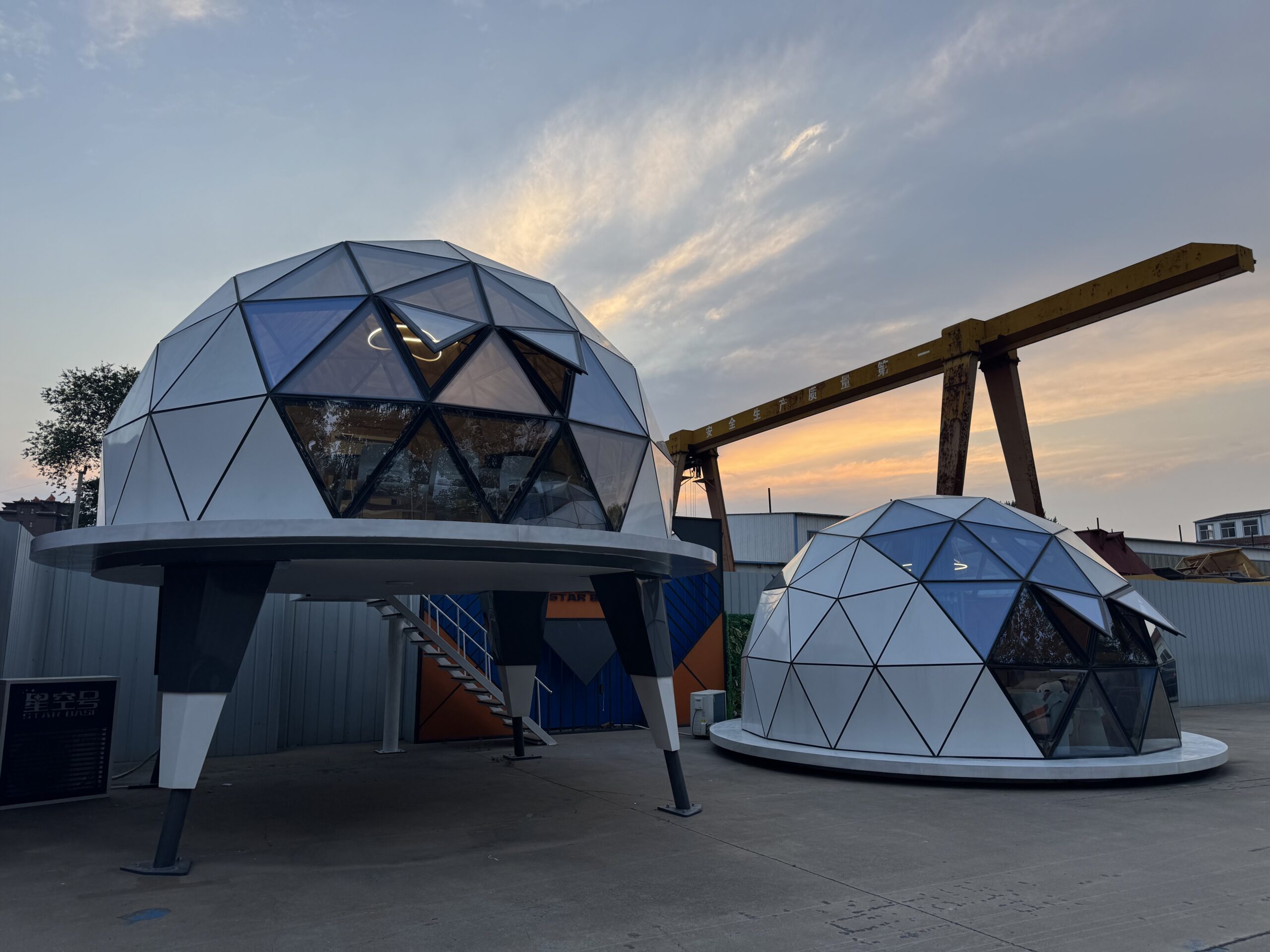 Two bahria homes House C7 Plus geodesic dome pods with sleek triangular glass panels and elevated modern design, showcasing innovative modular smart living solutions at sunset.