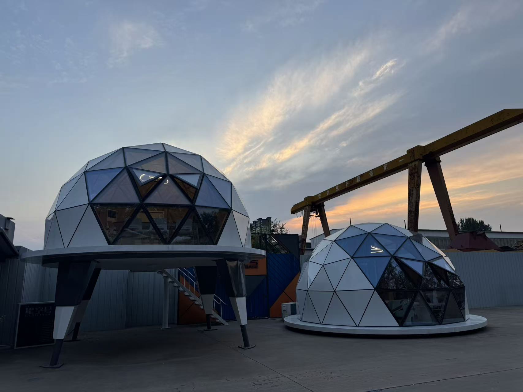 Two bahria homes House C7 Plus geodesic dome pods with triangular glass panels and sleek white exteriors, showcasing modern modular architecture at sunset.