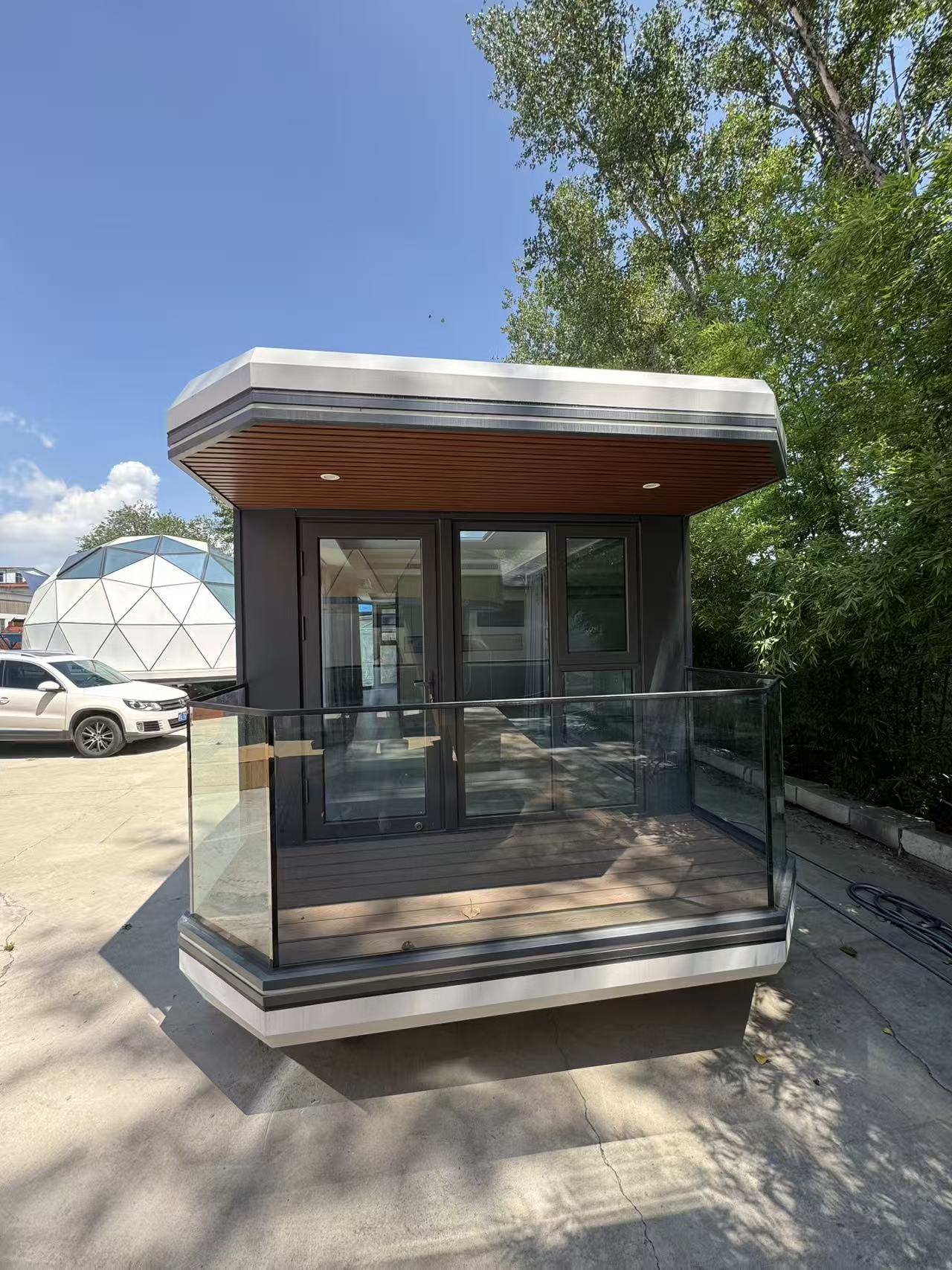 Front exterior view of the bahria homes House D5 modular smart pod featuring glass doors, sleek balcony design, and contemporary architecture surrounded by greenery.