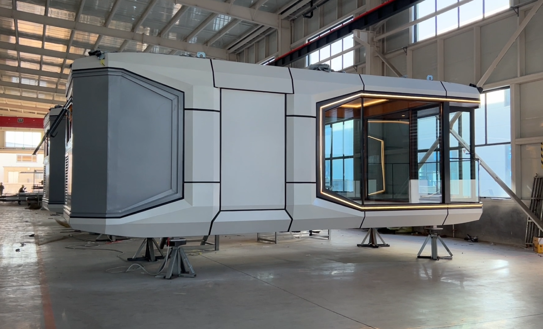 Side view of a modern bahria homes House modular pod under construction, featuring sleek geometric panels, large glass windows, and integrated LED lighting for smart living spaces.