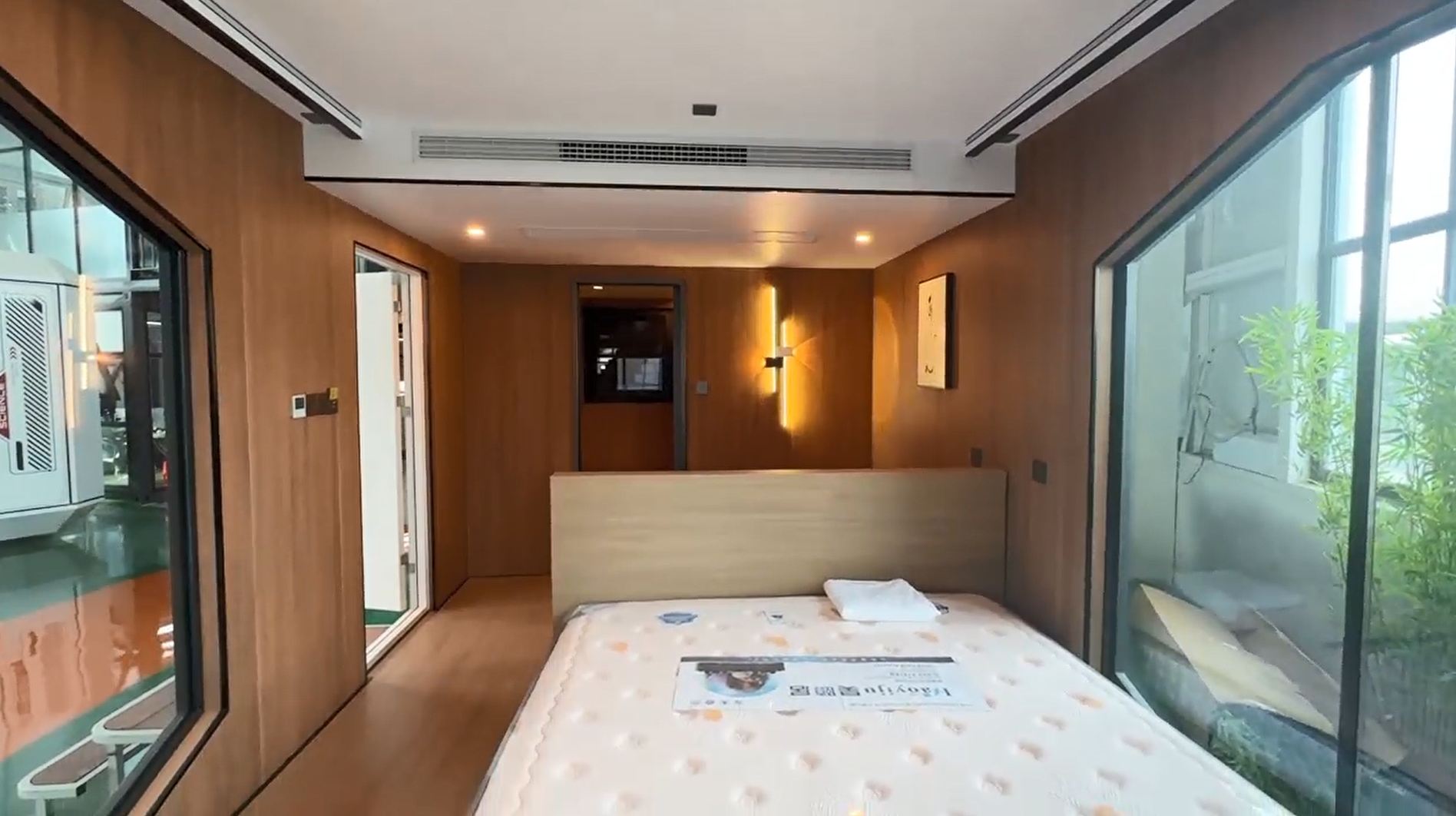 Interior of the bahria homes House D5 showcasing a contemporary bedroom with wooden paneling, large glass windows, integrated lighting, and minimalist smart home aesthetics.