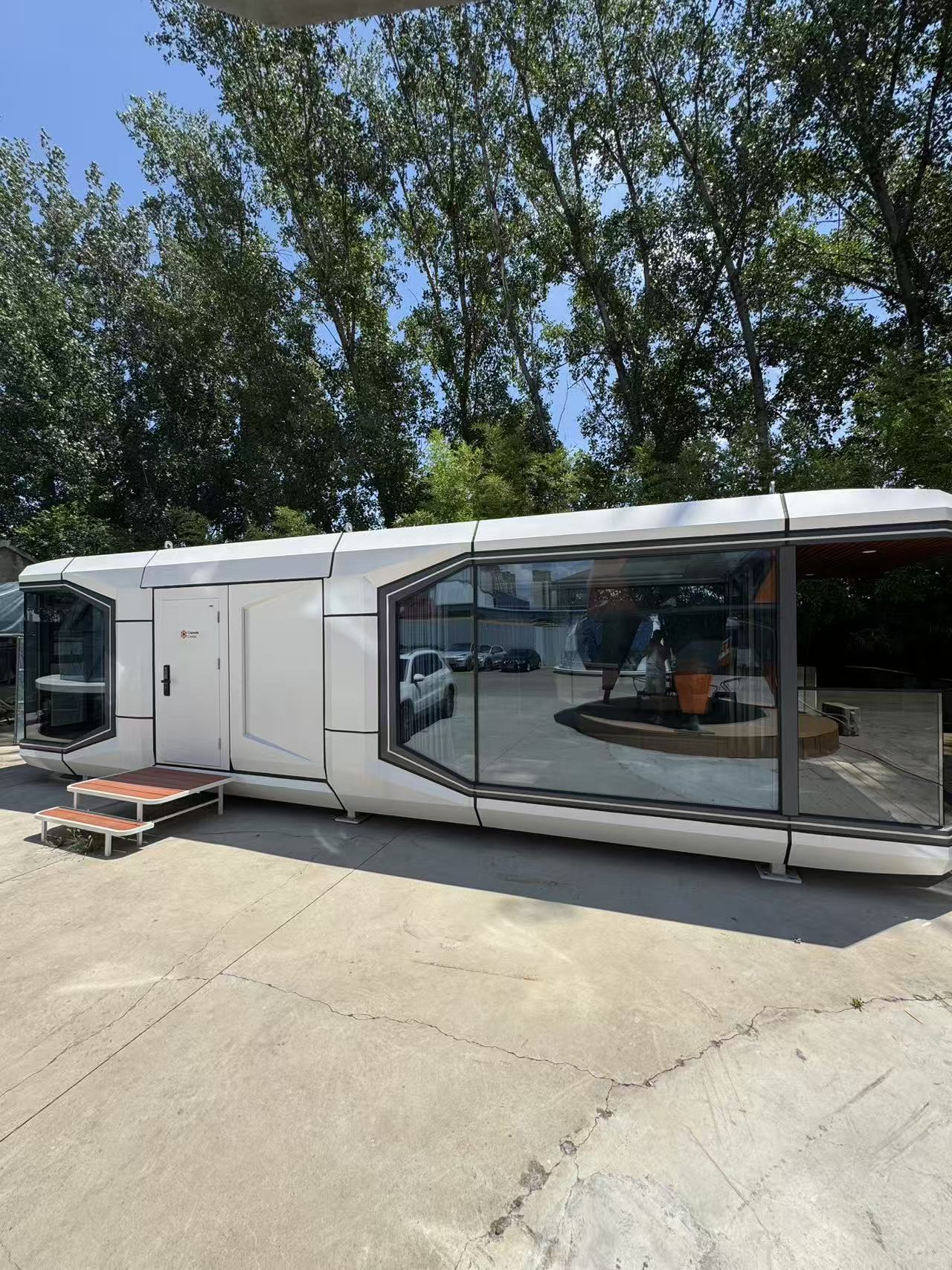 Outdoor view of the bahria homes House D7 modular smart pod featuring sleek geometric architecture, large glass panels, and minimalistic design surrounded by trees.